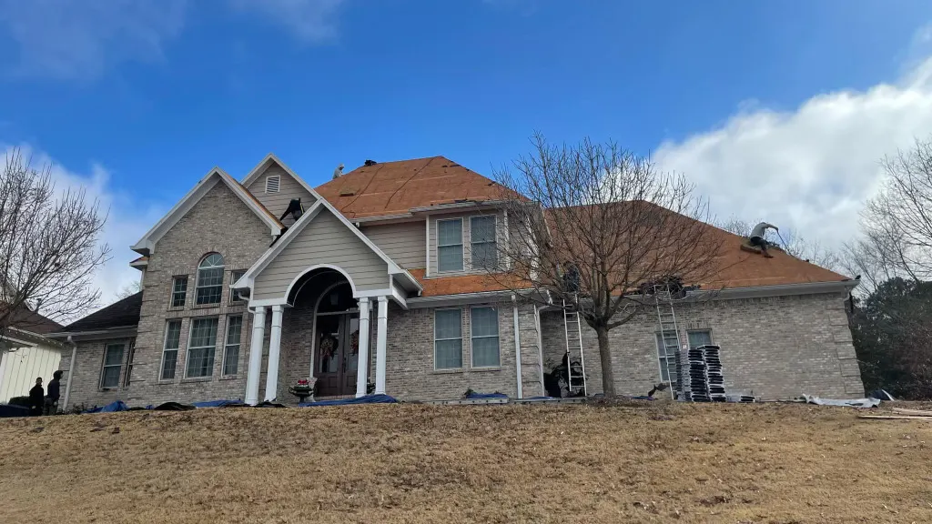 EcoPitch crew re-roofing a two-story brick home with arched, paired and single windows across the front